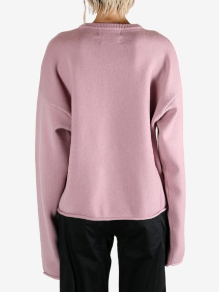 Pink knitwear worn by a person, showing the knitwear's fit